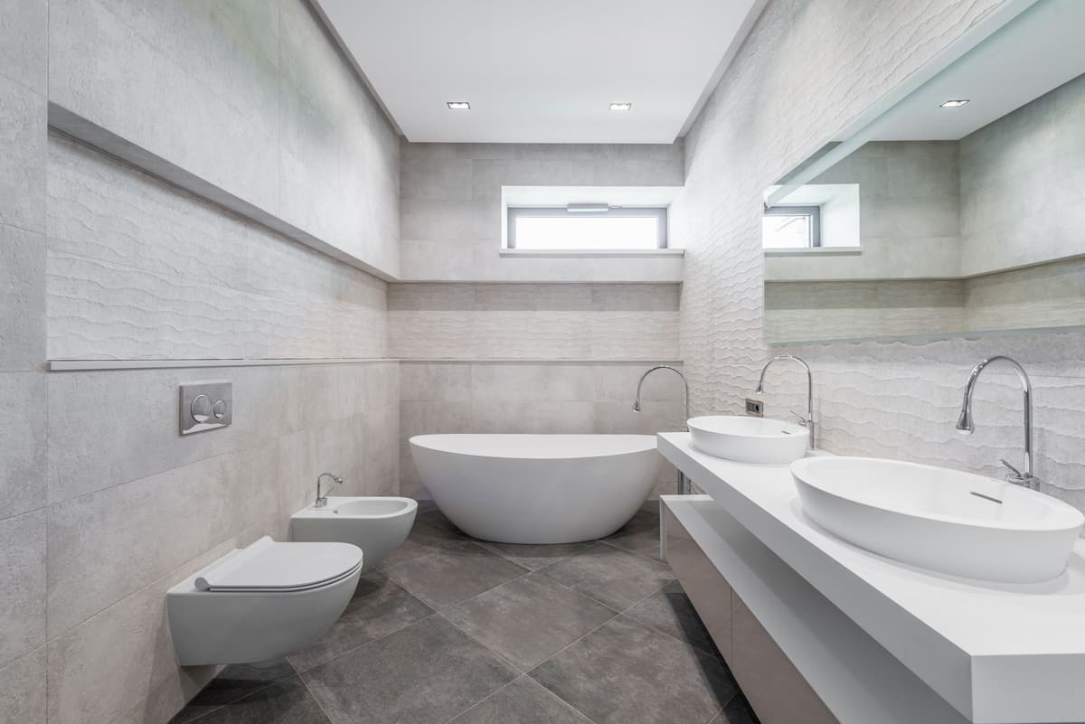 Minimalist stone-tiled bathroom with a freestanding tub and a double vessel-sink vanity