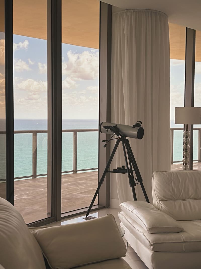 Living room with floor-to-ceiling windows, white leather sofas and an ocean view